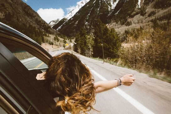 Picture of a woman riding a car feeling free. 