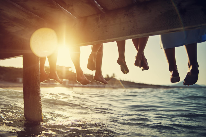 feet hanging off dock, sunset